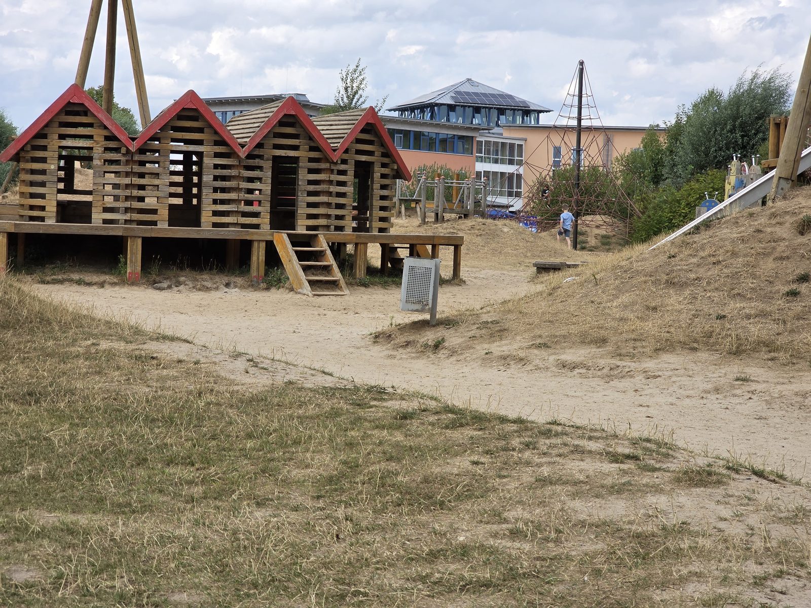 Sandspielplatz mit Holzhütten und Kletternetz im Brückenkopf-Park