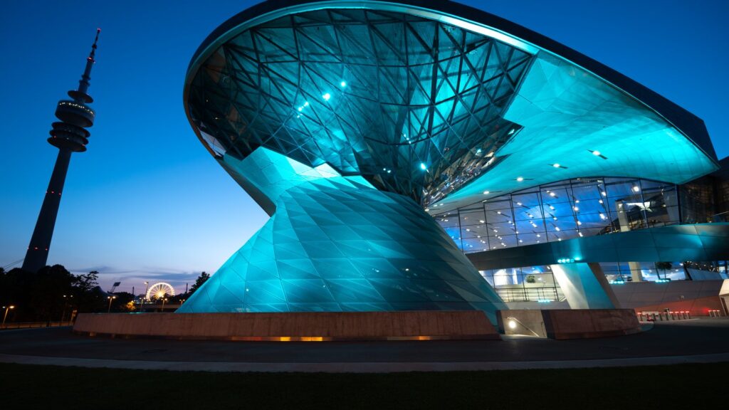 Beleuchteter Doppelkegel der BMW Welt und Olympiaturm in der blauen Stunde