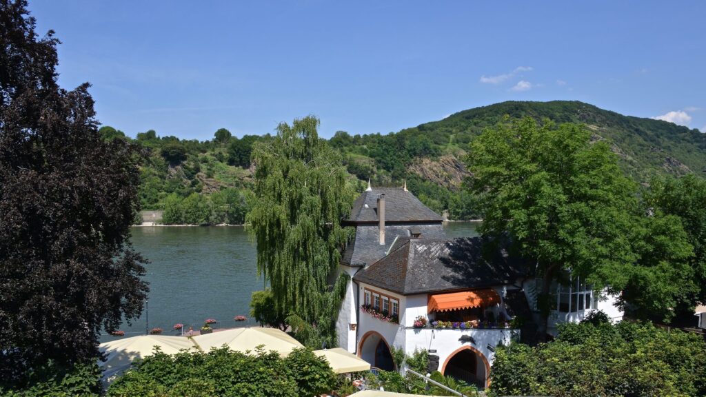 Rheinufer bei Boppard im Sommer mit altem Schieferdachhaus und bewaldeten Hängen