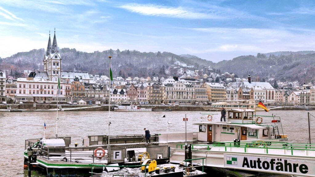 Verschneite Häuserzeile von Boppard am Rhein mit der Autofähre im Vordergrund