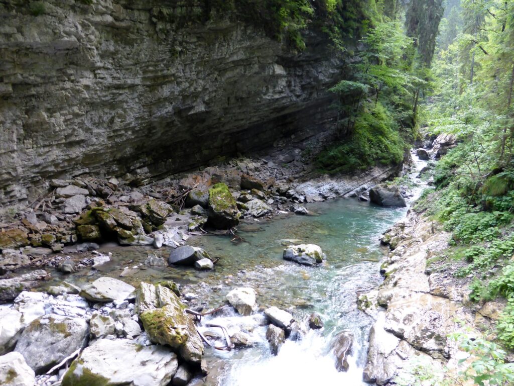 Überhängende Felswand über dem steinigen Bett der Breitach in der Klamm