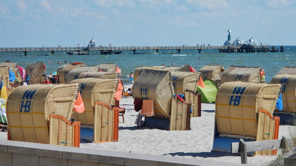 Strandkörbe am Grömitzer Sandstrand mit der Seebrücke im Hintergrund bei Sonnenschein