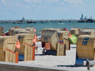 Strandkörbe am Grömitzer Sandstrand mit der Seebrücke im Hintergrund bei Sonnenschein