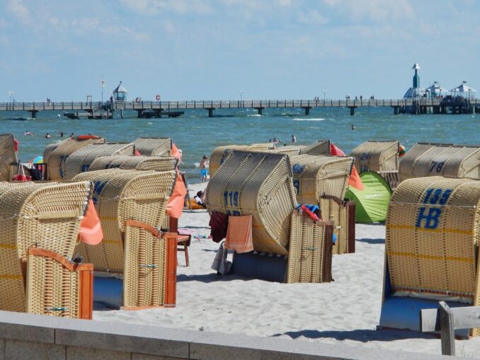 Strandkörbe am Grömitzer Sandstrand mit der Seebrücke im Hintergrund bei Sonnenschein