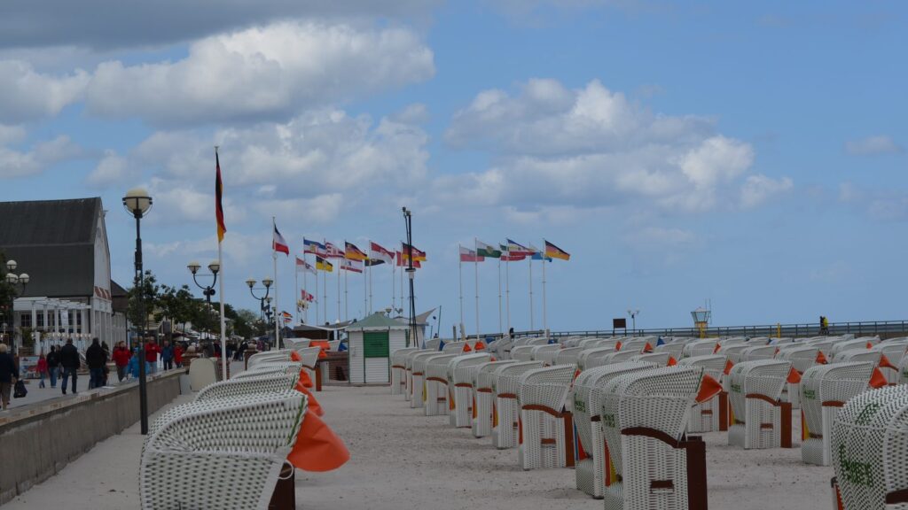 Kurpromenade in Grömitz mit Strandkörben, Fahnenmasten und Blick Richtung Seebrücke