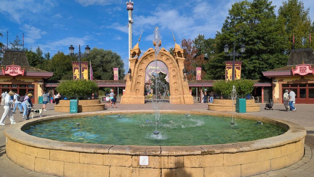 Eingangsportal von Plopsaland Deutschland mit Springbrunnen und Freifallturm dahinter