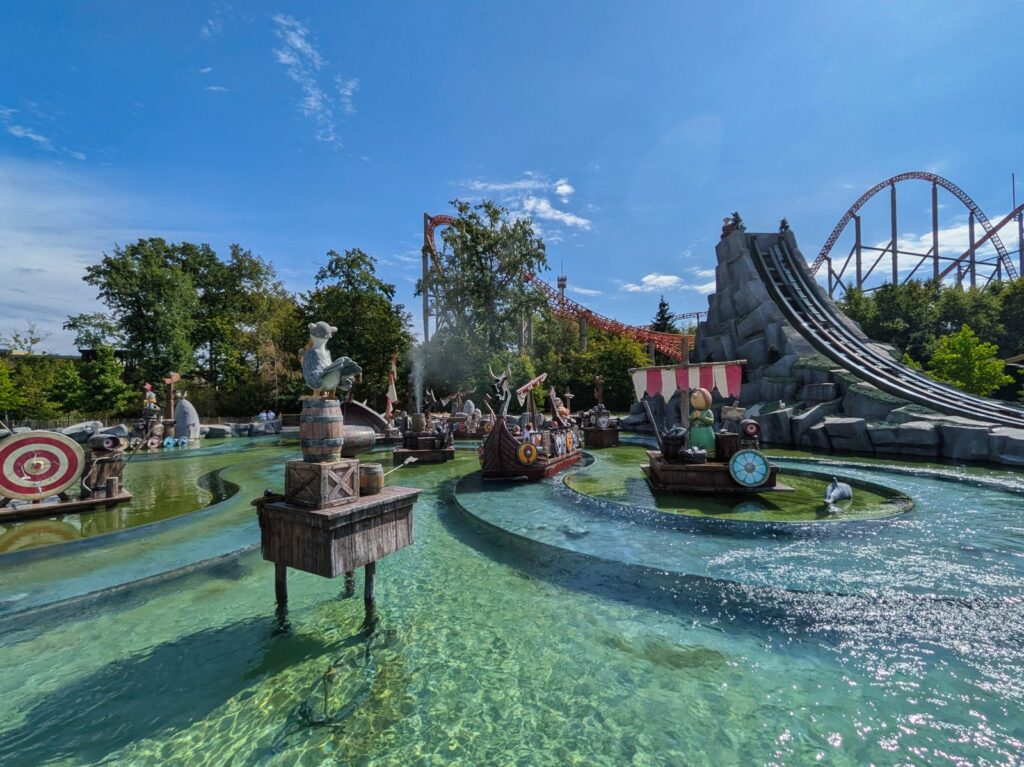 Wasserattraktion Splash Battle mit Wikingerbooten und Achterbahnschienen im Hintergrund