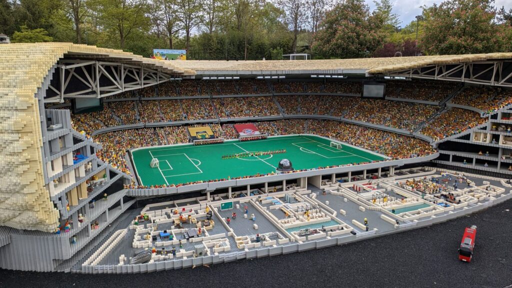 Aufgeschnittenes Fußballstadion aus Lego-Steinen mit gefüllten Rängen im Miniland