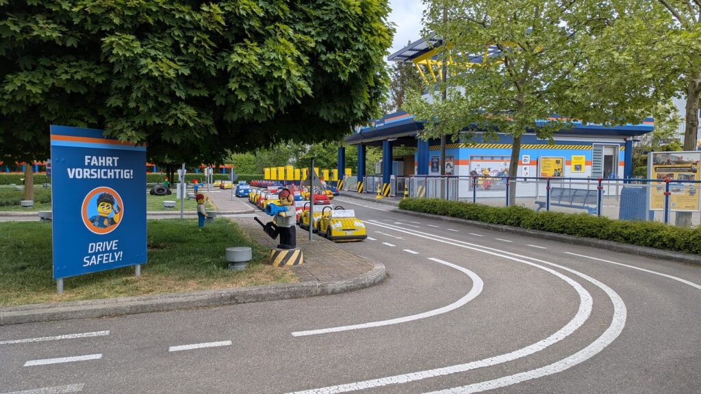 Übungsstraße der Verkehrsschule im Legoland mit Elektroautos und Hinweisschild