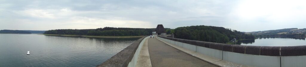 Panoramablick von der Mauerkrone über die Wasserfläche des Möhnesees und die bewaldeten Ufer