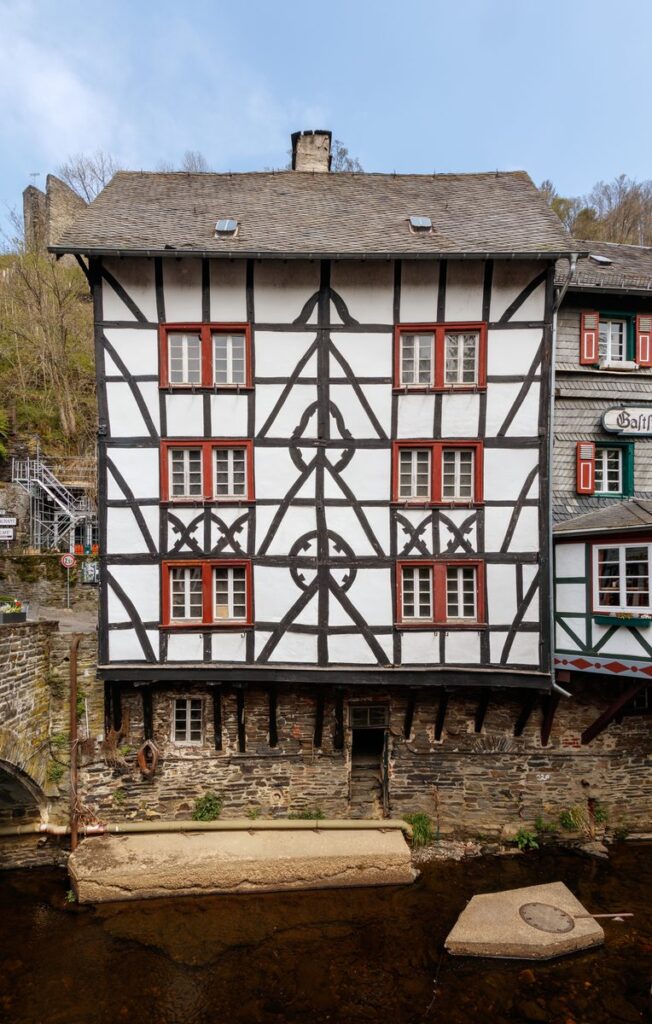 Fachwerkhaus mit Zierfachwerk steht auf Holzstützen über der Rur in Monschau