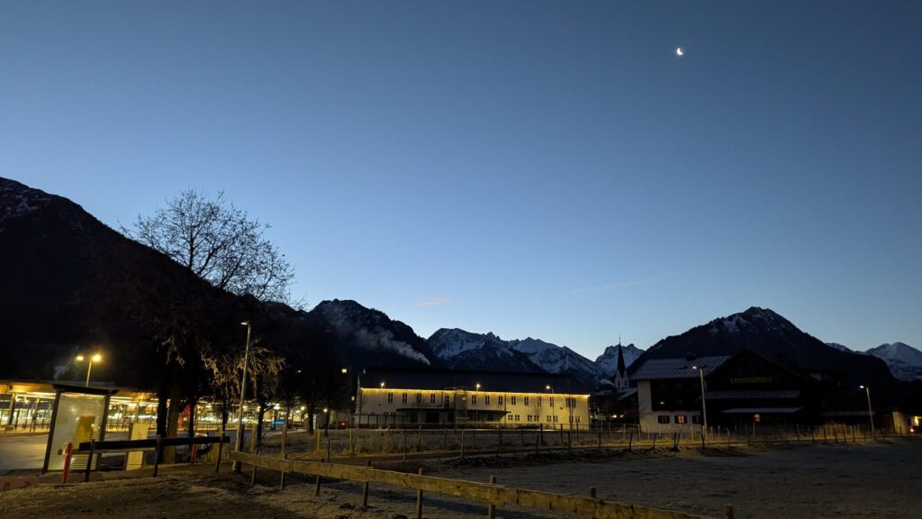 Oberstdorf zur blauen Stunde mit Kirchturm, Bahnhofsumfeld und verschneiten Gipfeln