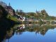 Saarburg mit Burgruine und Kirchturm spiegelt sich im Herbst in der Saar