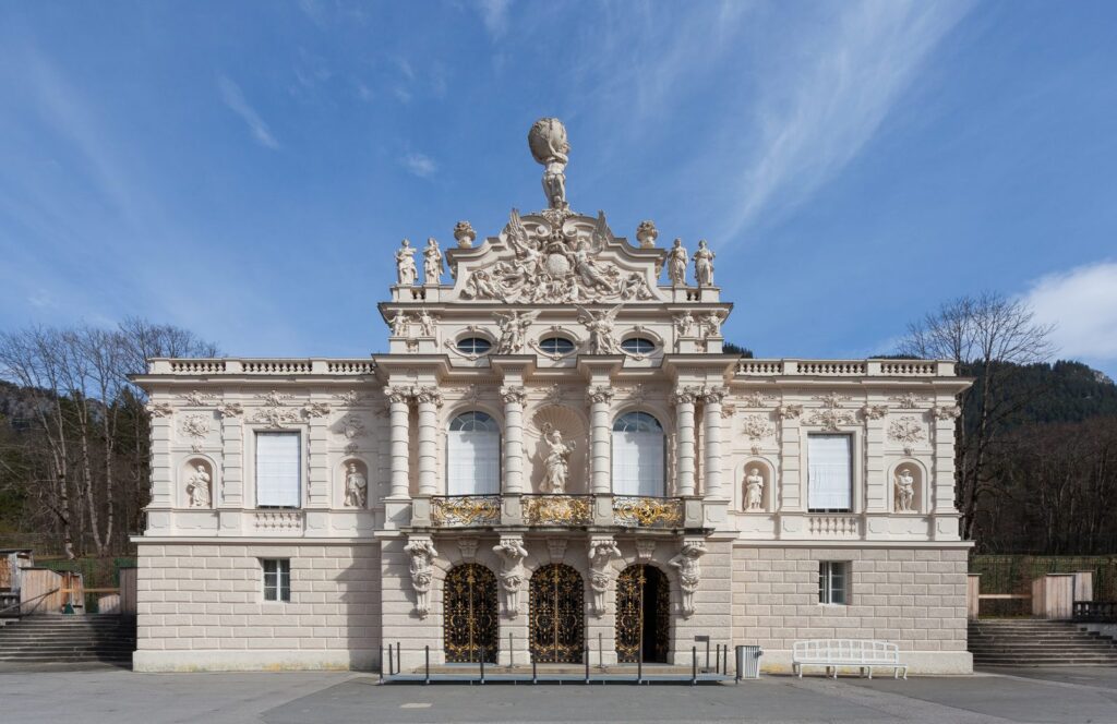 Reich verzierte Westfassade von Schloss Linderhof vor blauem Himmel