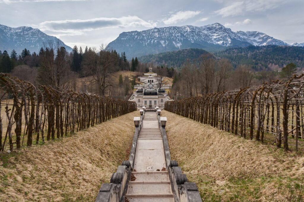 Blick über die Kaskade hinunter auf Schloss Linderhof vor verschneiten Bergen