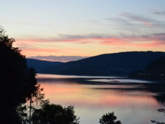 Abendrot über dem Schluchsee mit bewaldeten Schwarzwaldhöhen und dem Ort am Ufer