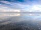Weite Wasserfläche des Steinhuder Meeres mit Wolkenspiegelung und flachem Uferstreifen am Horizont