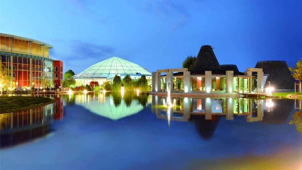 Therme Erding in der Abenddämmerung mit Glaskuppel, Saunadörfern und Badesee