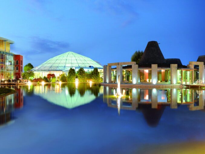 Therme Erding in der Abenddämmerung mit Glaskuppel, Saunadörfern und Badesee