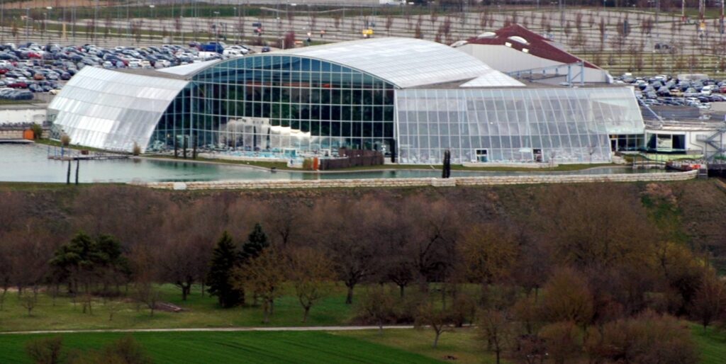 Verglaste Thermenhalle der Badewelt Sinsheim mit Badesee und Liegewiese davor