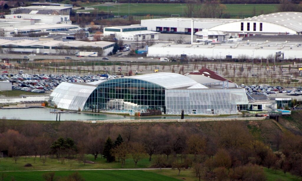 Badewelt Sinsheim im Gewerbegebiet, dahinter Ausstellungshallen und große Parkflächen