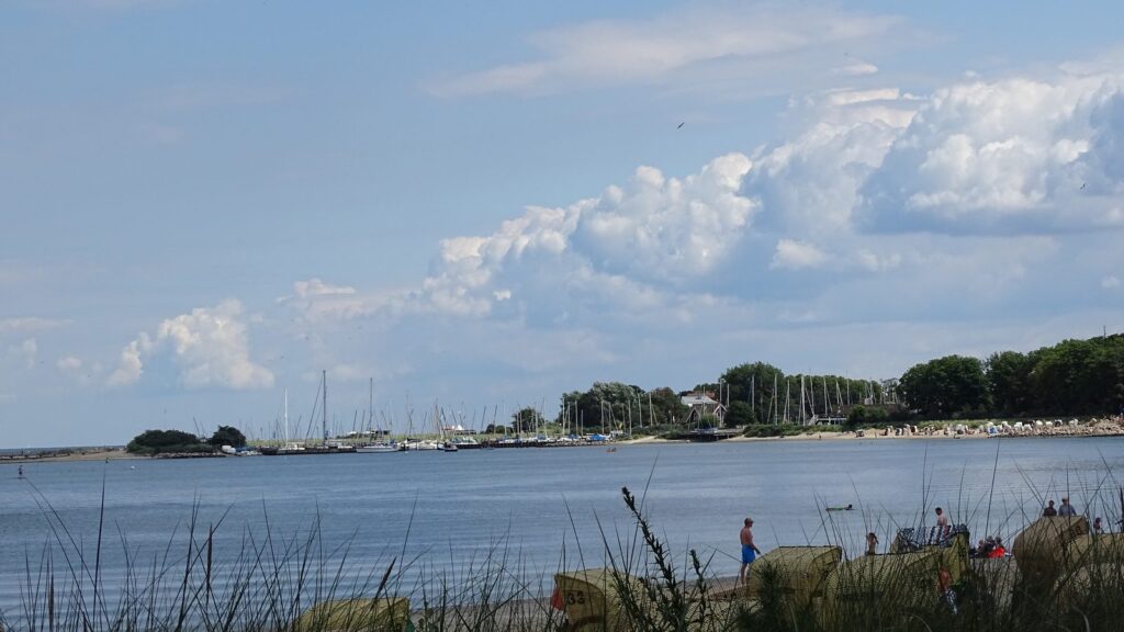 Strandkörbe am Ufer der Lübecker Bucht mit dem Segelhafen Niendorf im Hintergrund