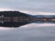 Blick vom Seerundweg über den Titisee auf den Ort mit Kirchturm und bewaldeten Hängen