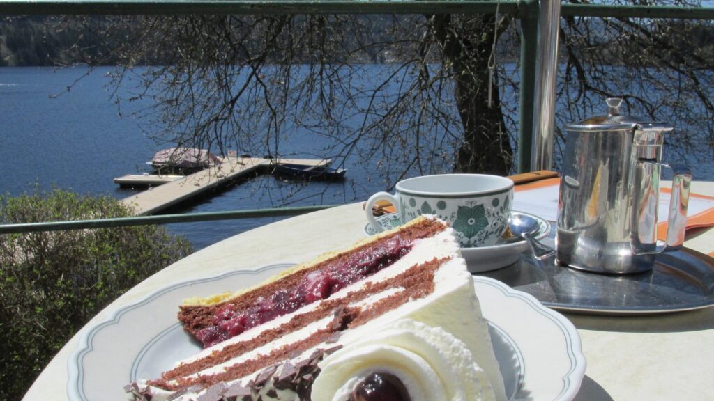 Stück Schwarzwälder Kirschtorte auf einer Caféterrasse am Ufer des Titisees