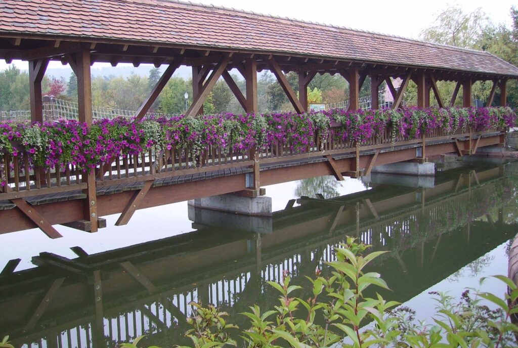 Gedeckte Holzbrücke mit Blumenkästen über dem Teich im Erlebnispark Tripsdrill