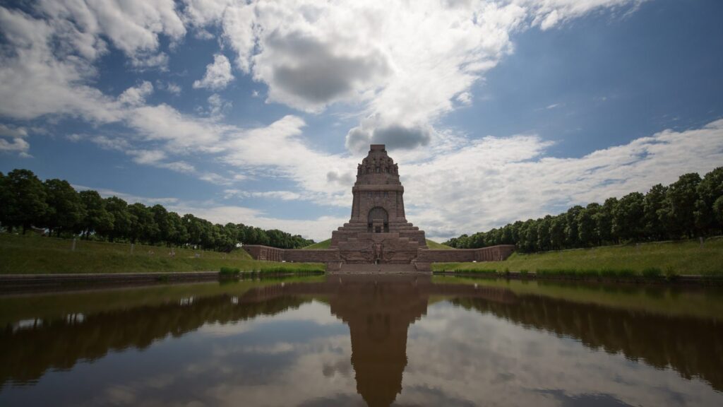 Völkerschlachtdenkmal mit Wolkenhimmel und Spiegelung im Wasserbecken der Anlage