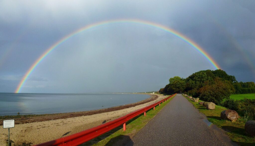 Regenbogen über der Ostsee am Weissenhäuser Strand mit Sandstrand und Küstenweg