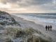 Leerer Nordseestrand im Winter mit Dünengras und tief stehender Sonne