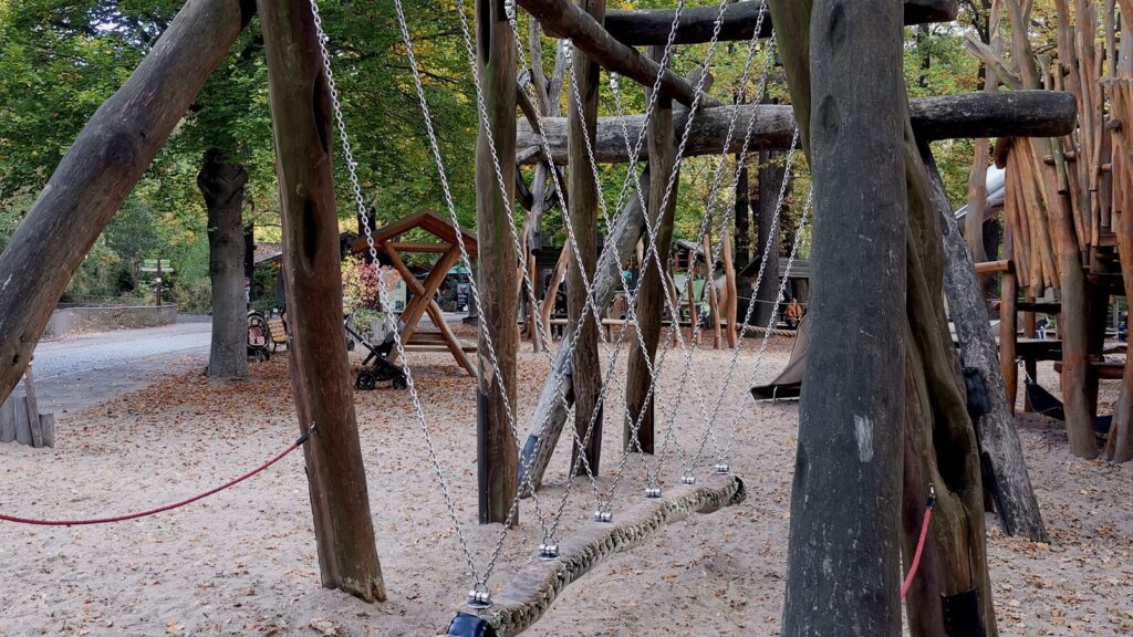 Klettergerüst aus Holzstämmen mit Seilbrücke auf dem Spielplatz im Zoo Berlin